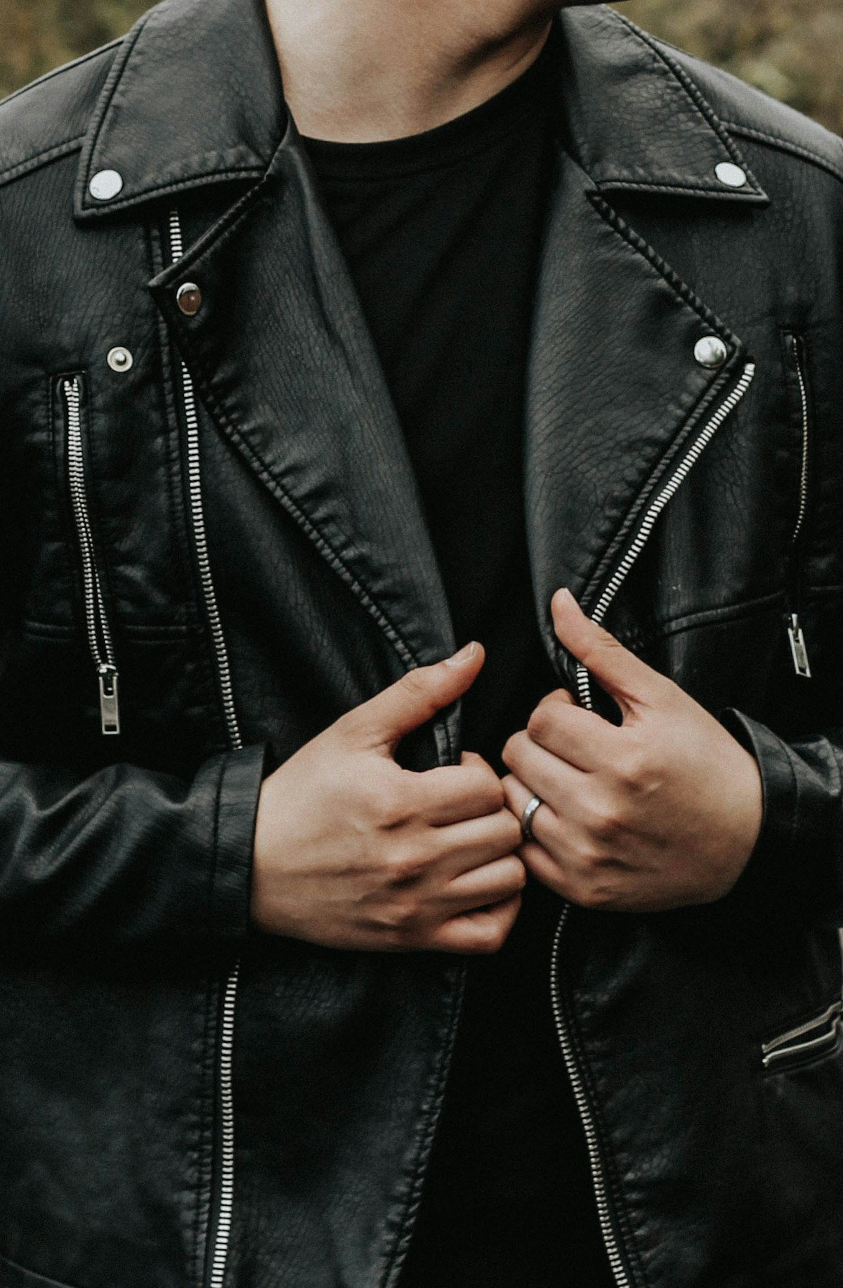 Close-up of a stitched leather lapel with studs and zips on a black biker jacket