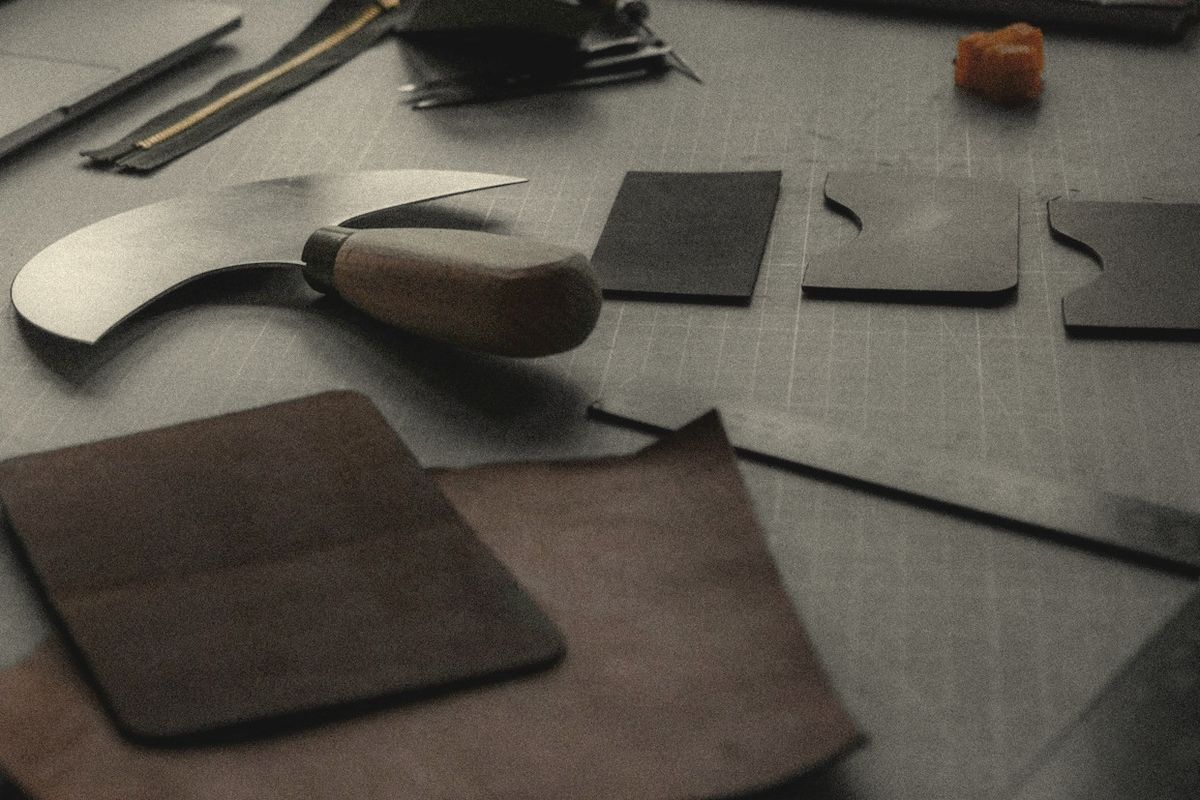Round knife and leather panels on a workshop cutting table