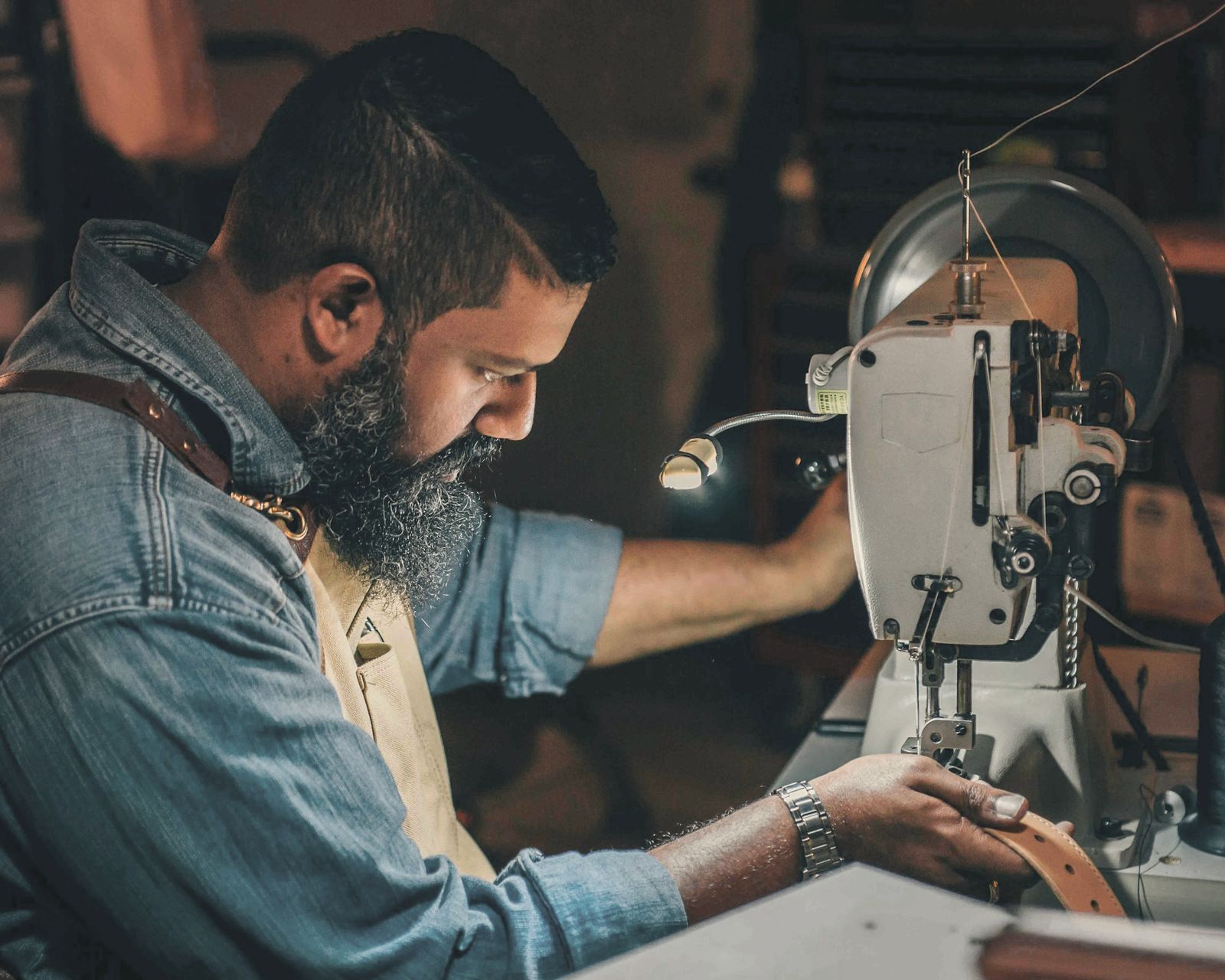 Leatherworker feeding a belt through an industrial sewing machine