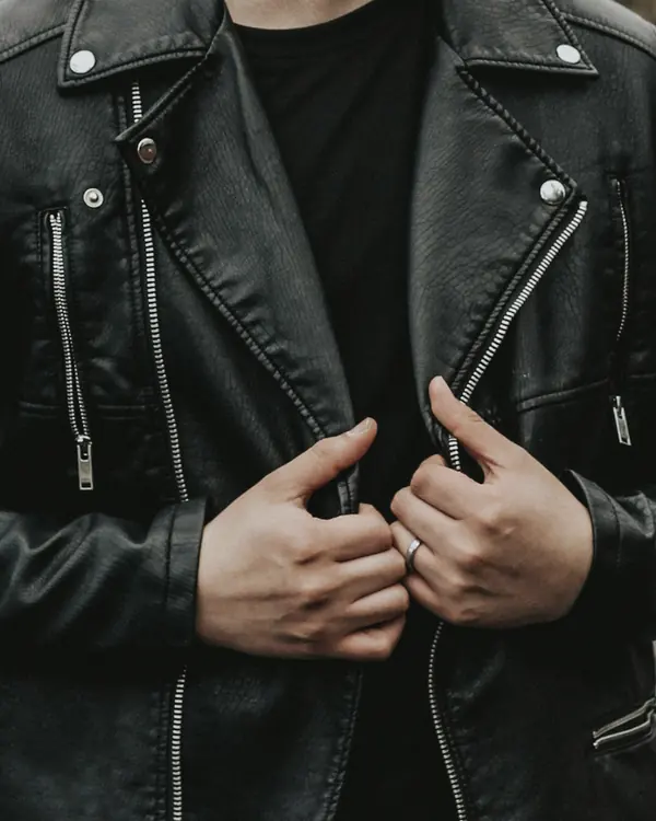 Detail of the asymmetric zip, snap lapels and zipped chest pocket, with hands holding the lapels